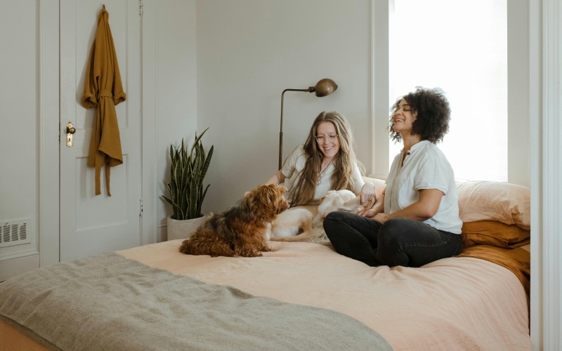 friends sitting on a bed with a dog